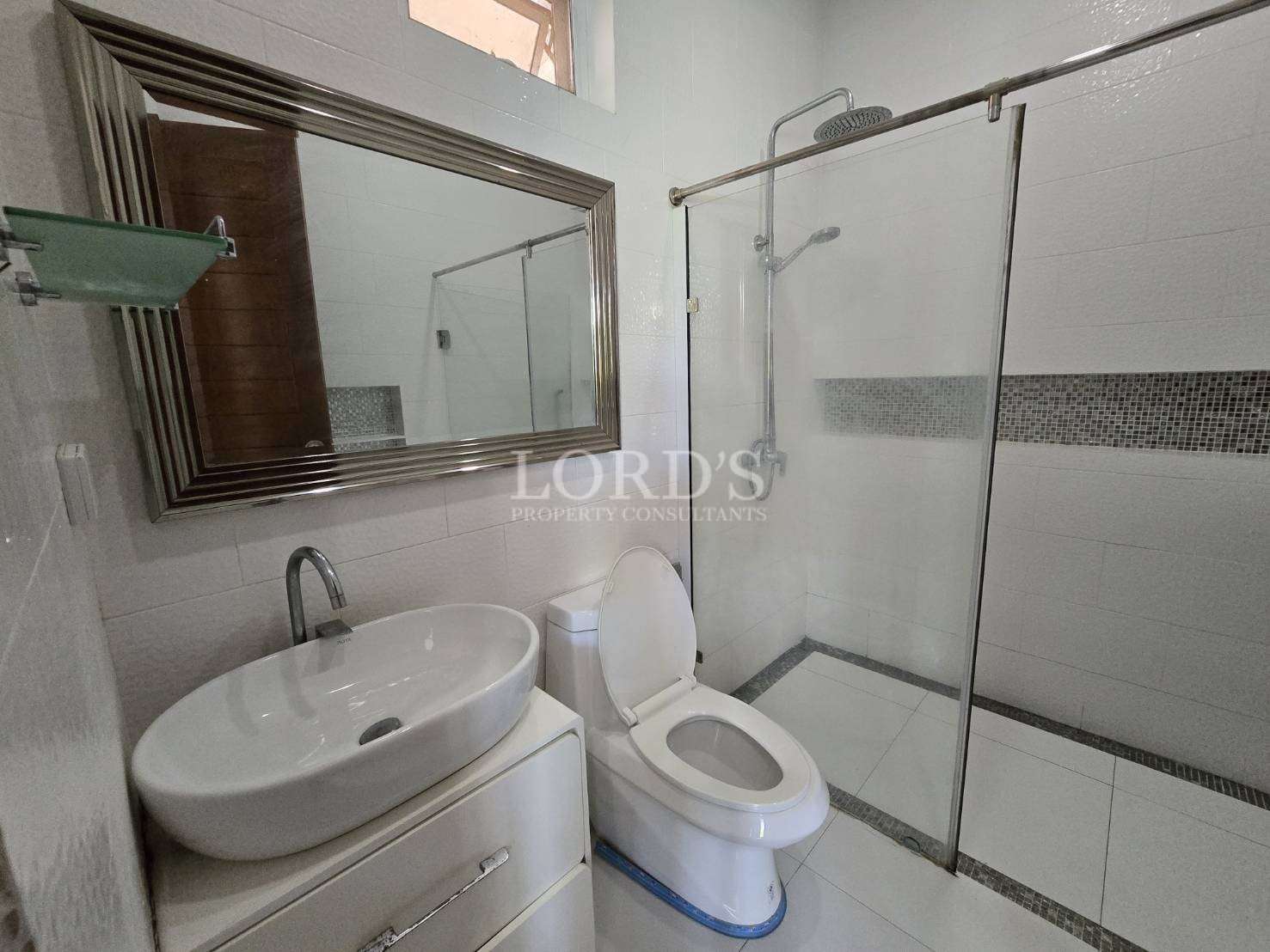 Modern bathroom with glass shower enclosure, vanity sink, and toilet.