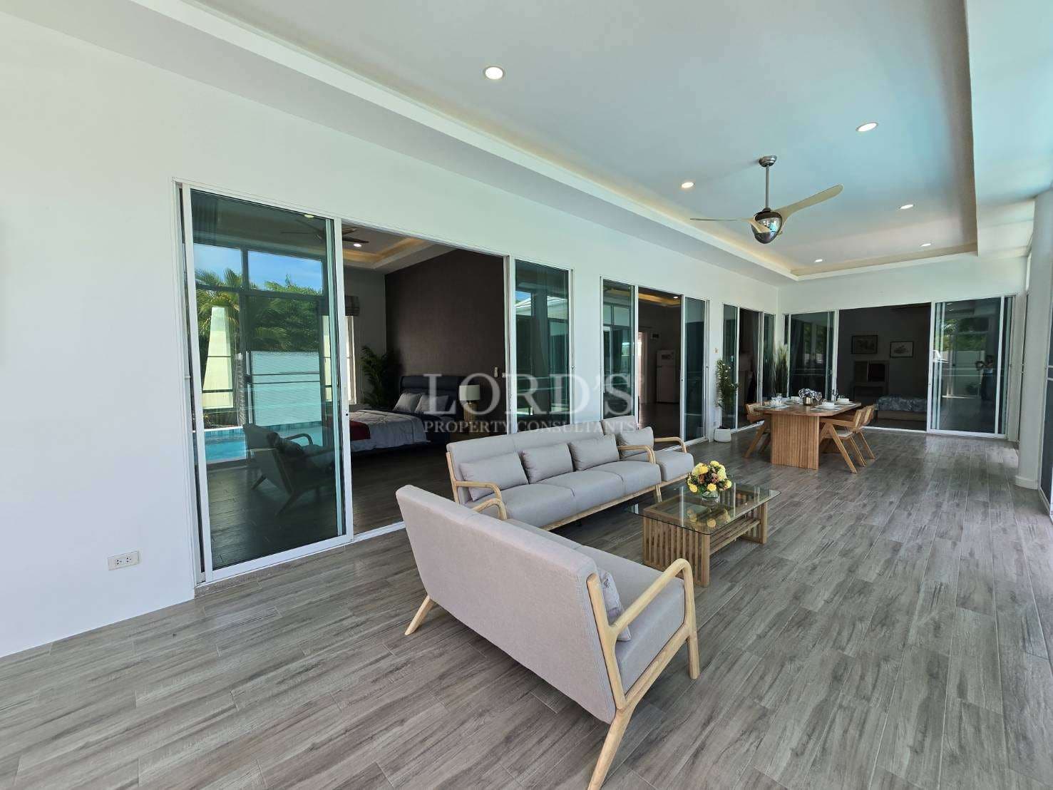 Covered terrace with outdoor seating, sliding glass doors, and open-plan indoor living areas.