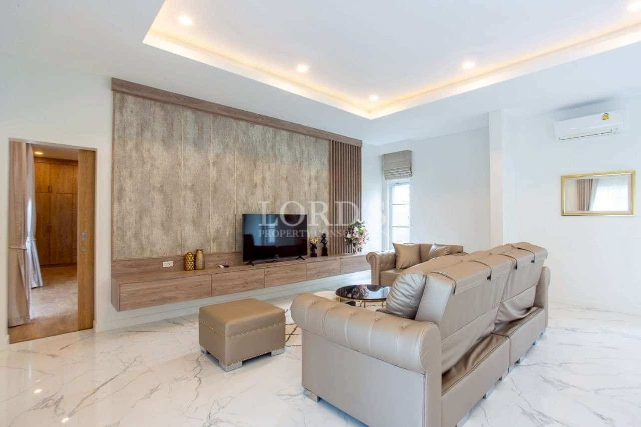 Modern living room with built-in TV wall, marble flooring, and recessed ceiling lighting.