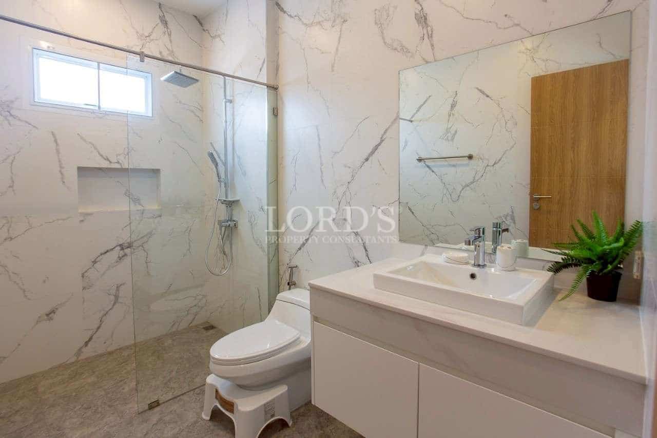 Modern bathroom with glass shower enclosure and marble-effect wall tiles.