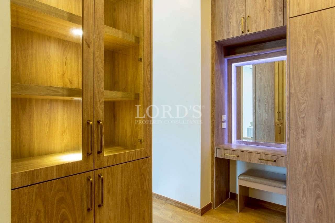 Built-in wooden wardrobe and dressing table with illuminated mirror.