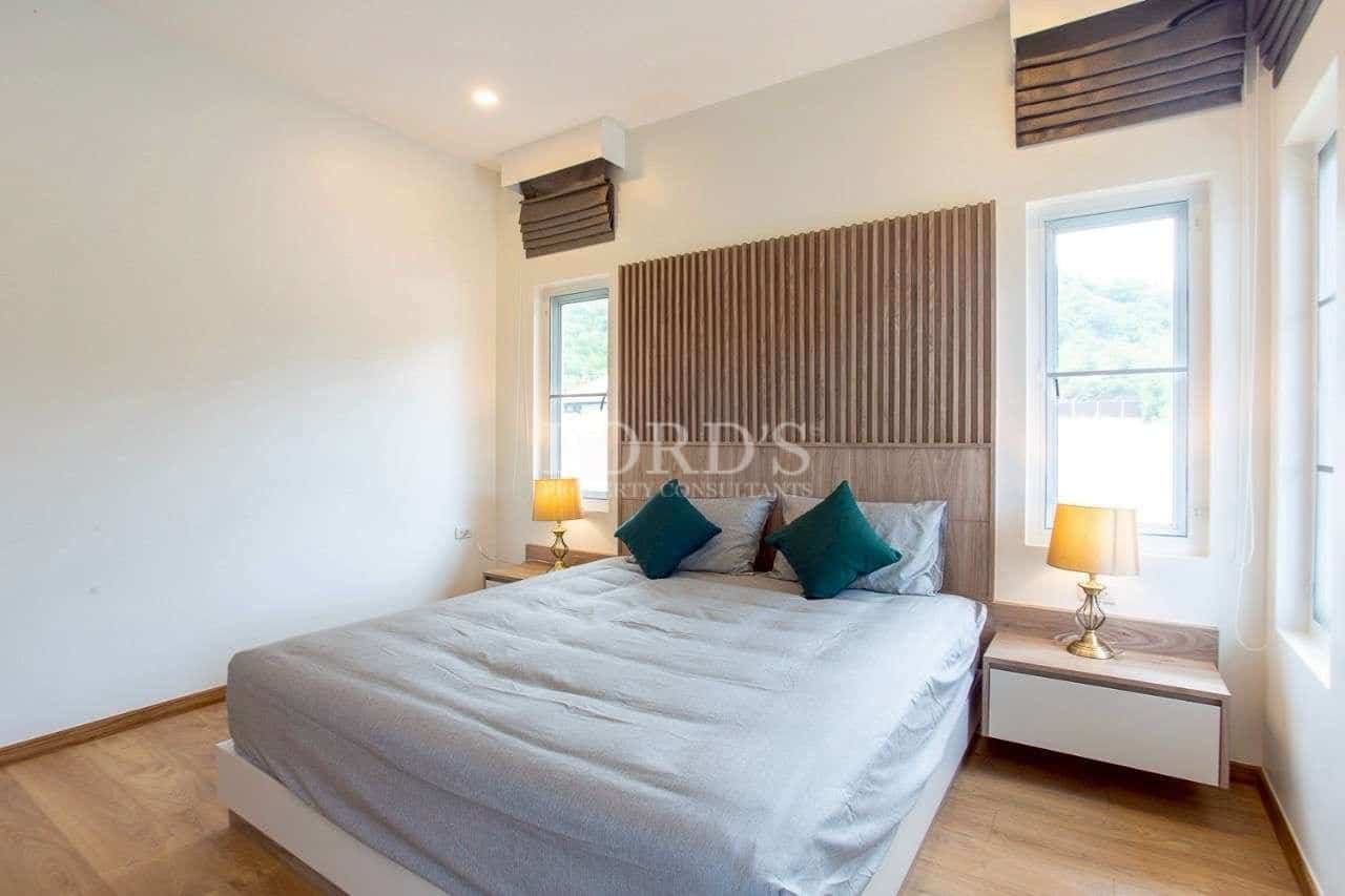 Modern bedroom with wood accent headboard, neutral tones, and soft ambient lighting.