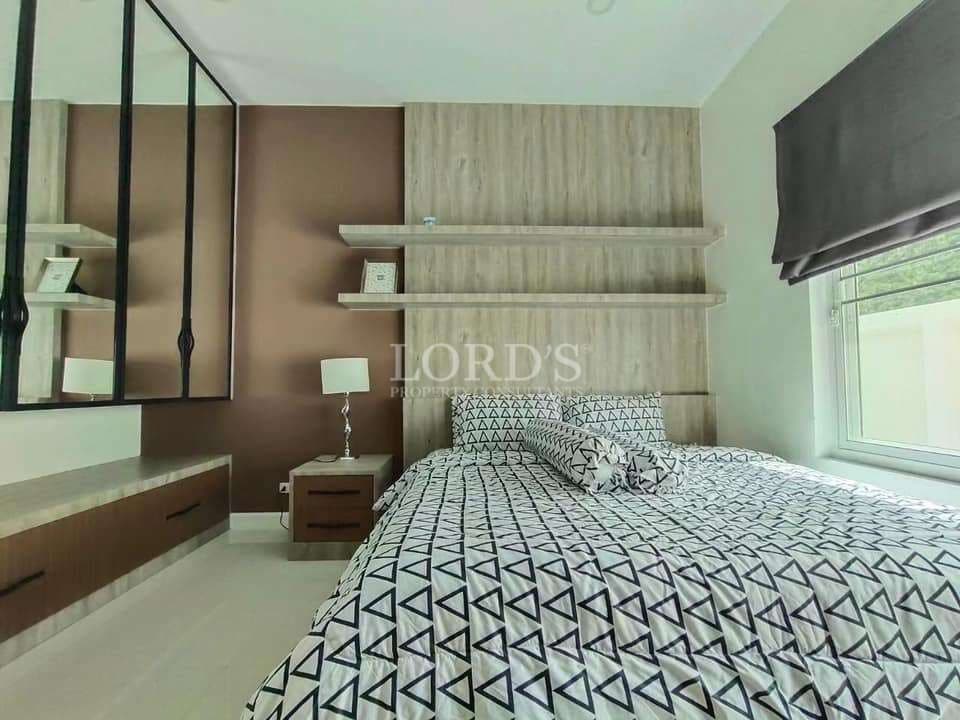 Modern bedroom with minimalist design, patterned bedding, floating shelves, and built-in vanity.