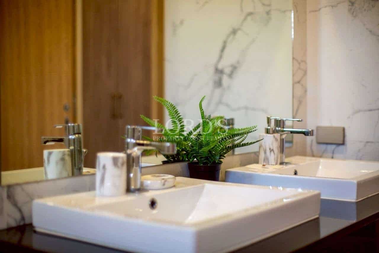 Close-up of modern bathroom double sink with chrome fixtures and marble-style finishes.