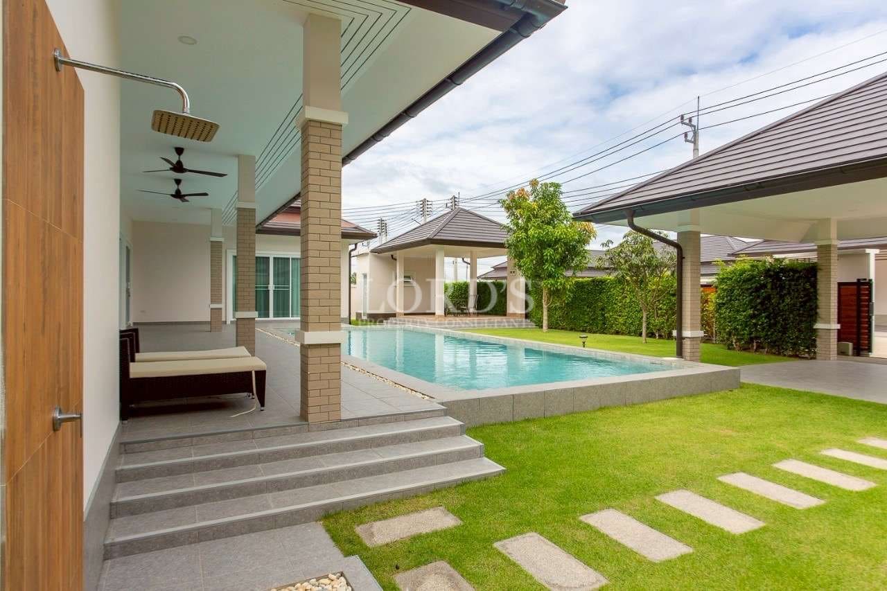 Covered terrace with outdoor shower, private swimming pool, and landscaped garden at modern villa.