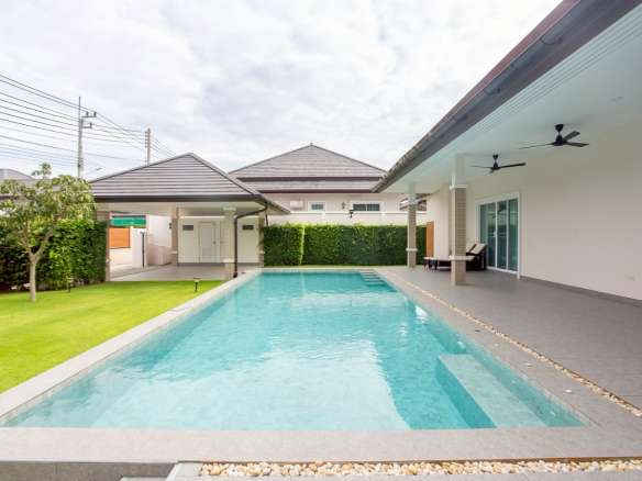 Modern single-story villa with a private swimming pool, covered patio, ceiling fans, and landscaped garden.