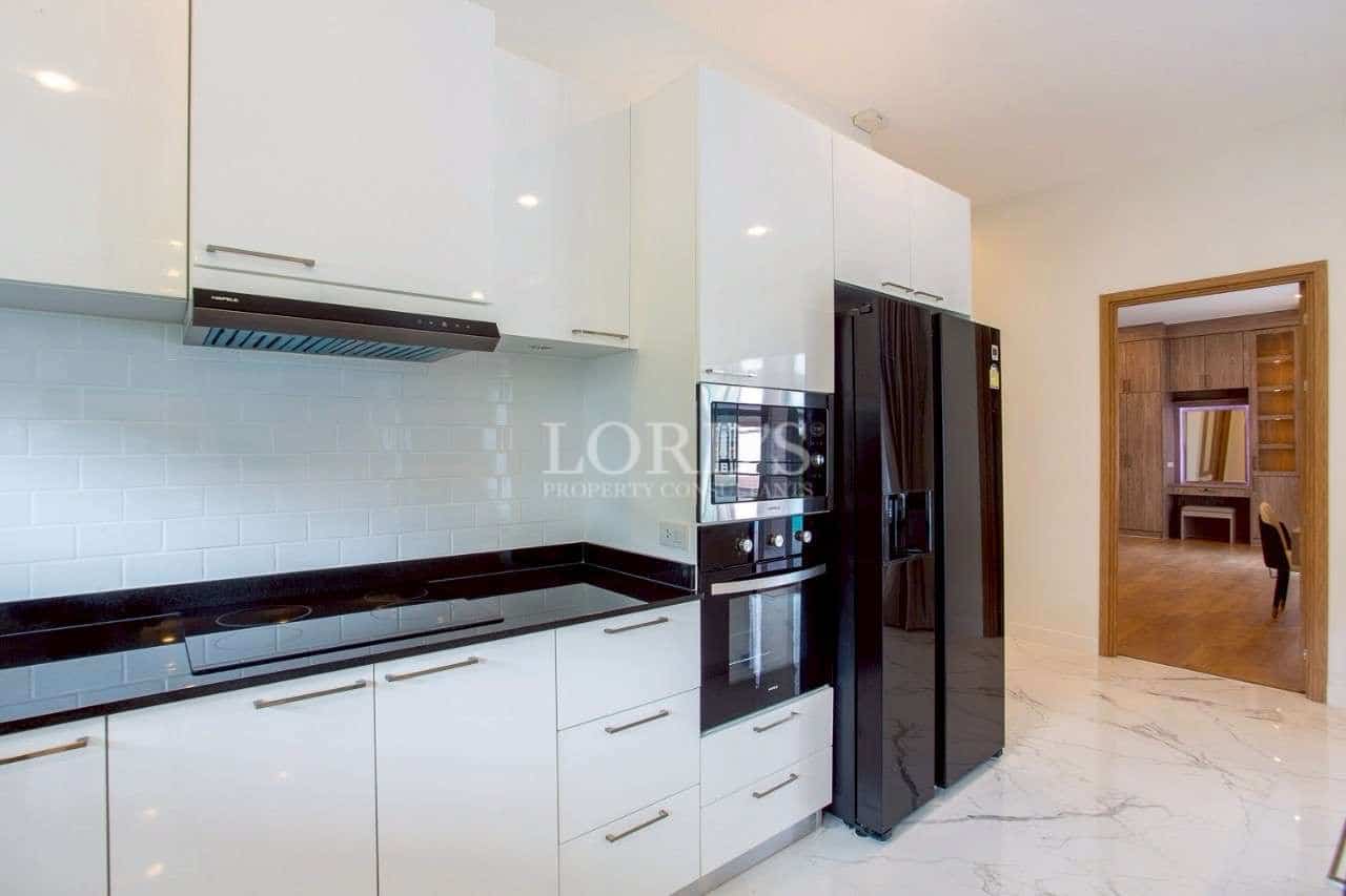 Bright modern kitchen with glossy white cabinets, built-in oven, and black refrigerator.
