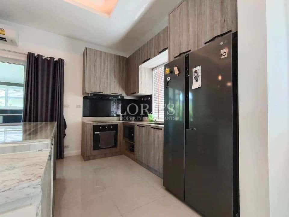 Modern L-shaped kitchen with built-in appliances and wood-finish cabinetry.