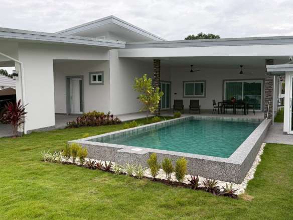 Modern single-story villa with raised private swimming pool, covered patio, and landscaped lawn.