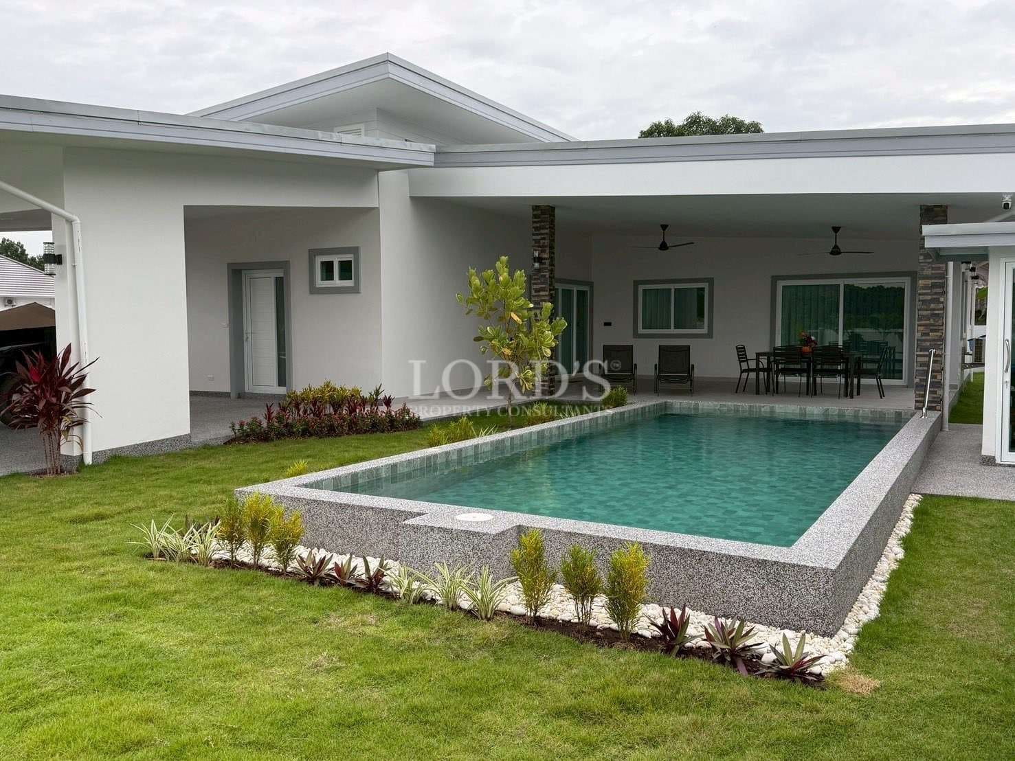 Modern single-story villa with raised private swimming pool, covered patio, and landscaped lawn.