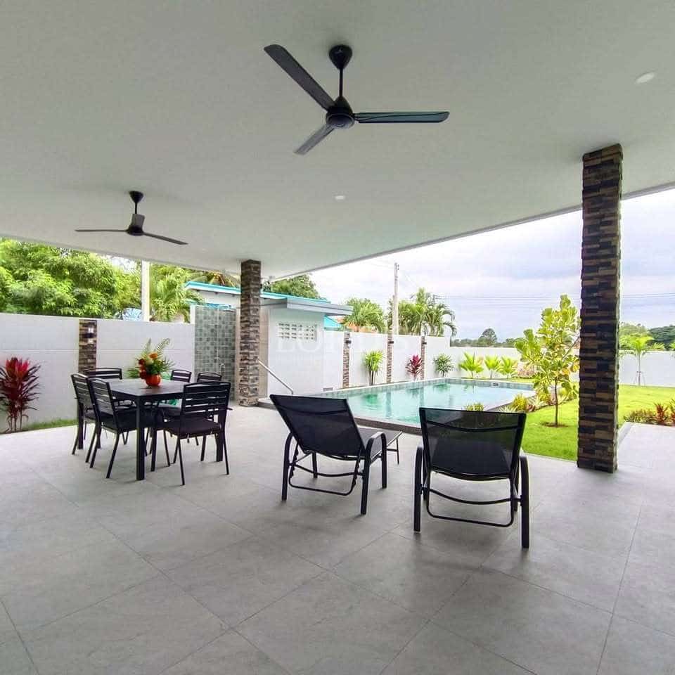 Covered outdoor patio with ceiling fans, dining set, lounge chairs, and swimming pool