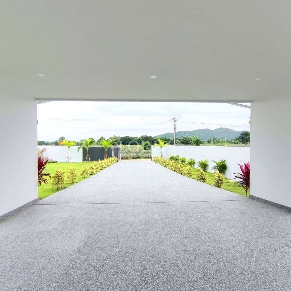 Covered driveway with landscaped garden, paved flooring, and open view toward greenery and hills