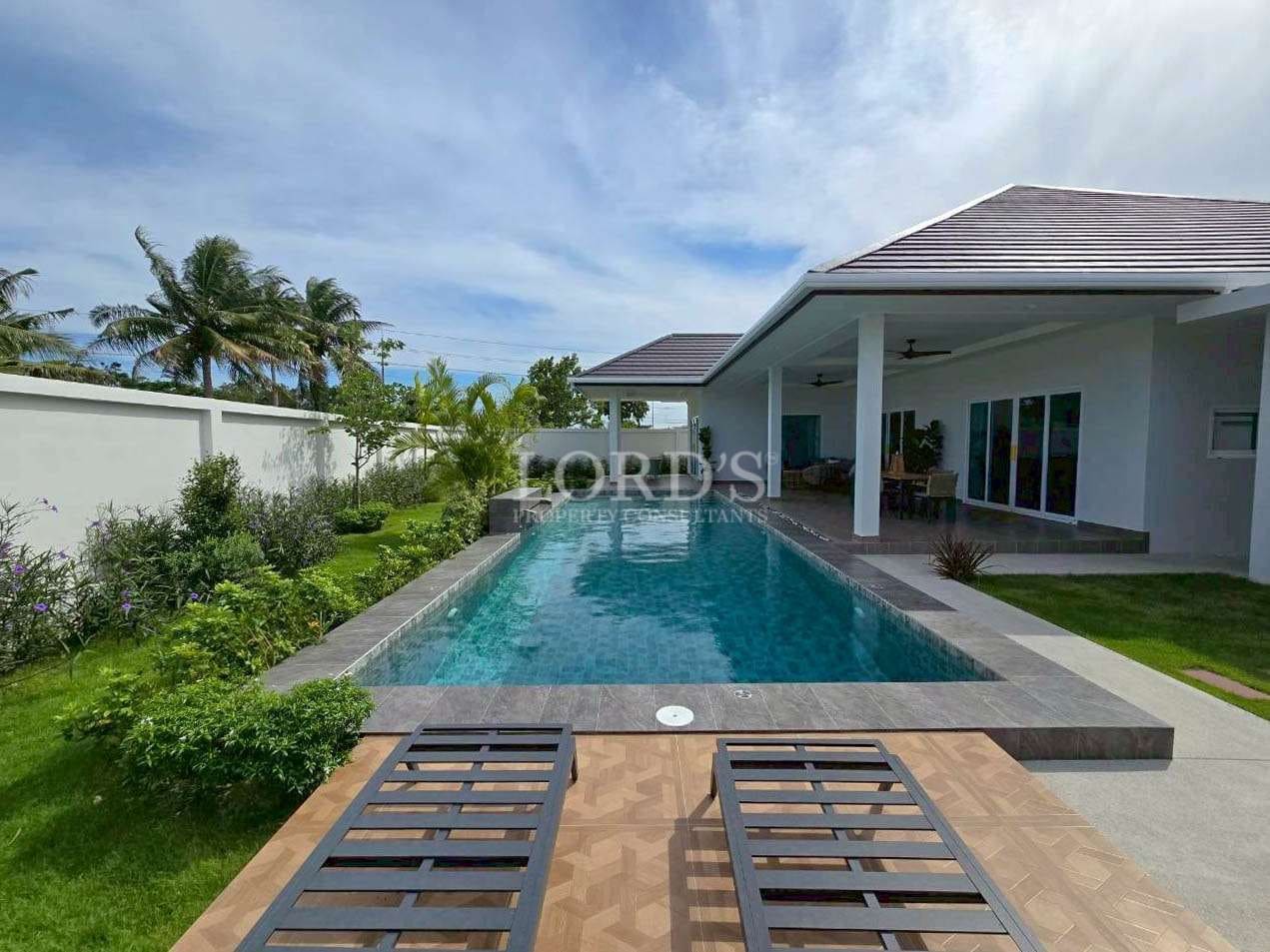 Private swimming pool with sun loungers, landscaped garden, and covered outdoor terrace.