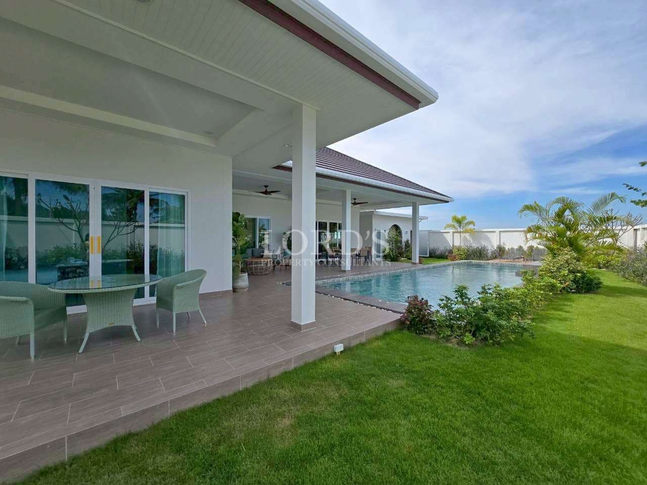 Covered poolside terrace with outdoor seating, landscaped lawn, and private swimming pool.