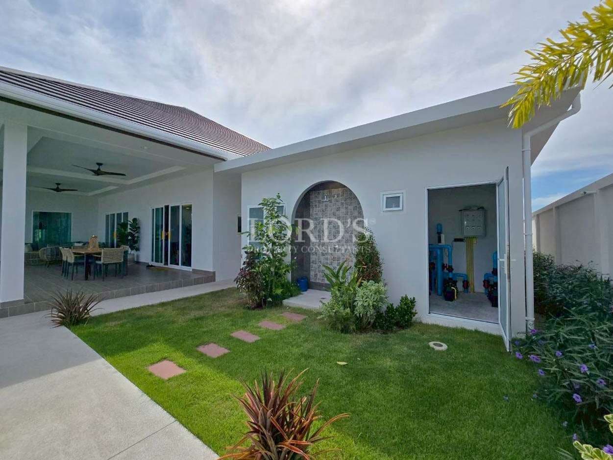 Landscaped garden with covered terrace, outdoor dining area, and separate utility room.