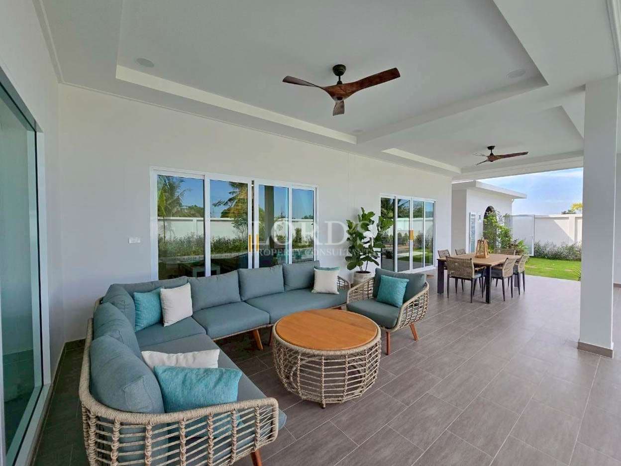 Covered outdoor lounge and dining area with ceiling fans and garden views.