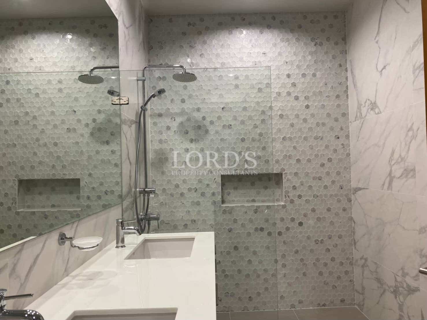 Modern walk-in shower with hexagon mosaic tiles, glass partition, built-in niche, and dual shower fixtures.