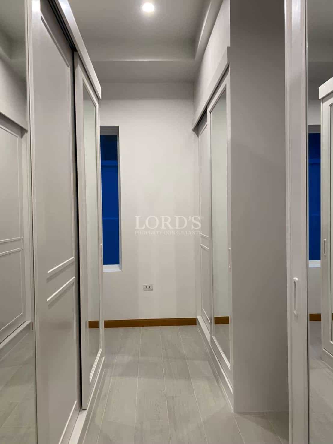 Walk-in closet corridor with mirrored wardrobe doors, built-in storage, and modern recessed lighting.