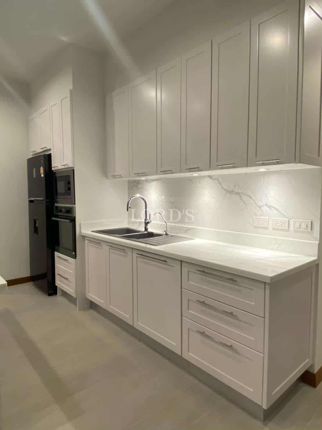 Modern kitchen with full-height white cabinetry, marble-look backsplash, built-in appliances, and sleek countertops.