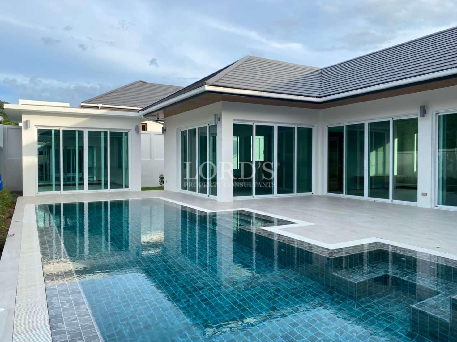 Modern luxury villa with a private swimming pool, large glass doors, and a spacious poolside terrace.