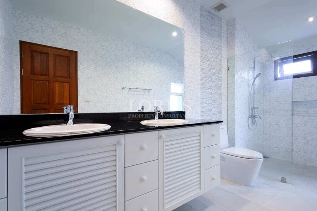 Spacious modern bathroom with double sink vanity, black countertop, glass-enclosed shower, and bright natural lighting.