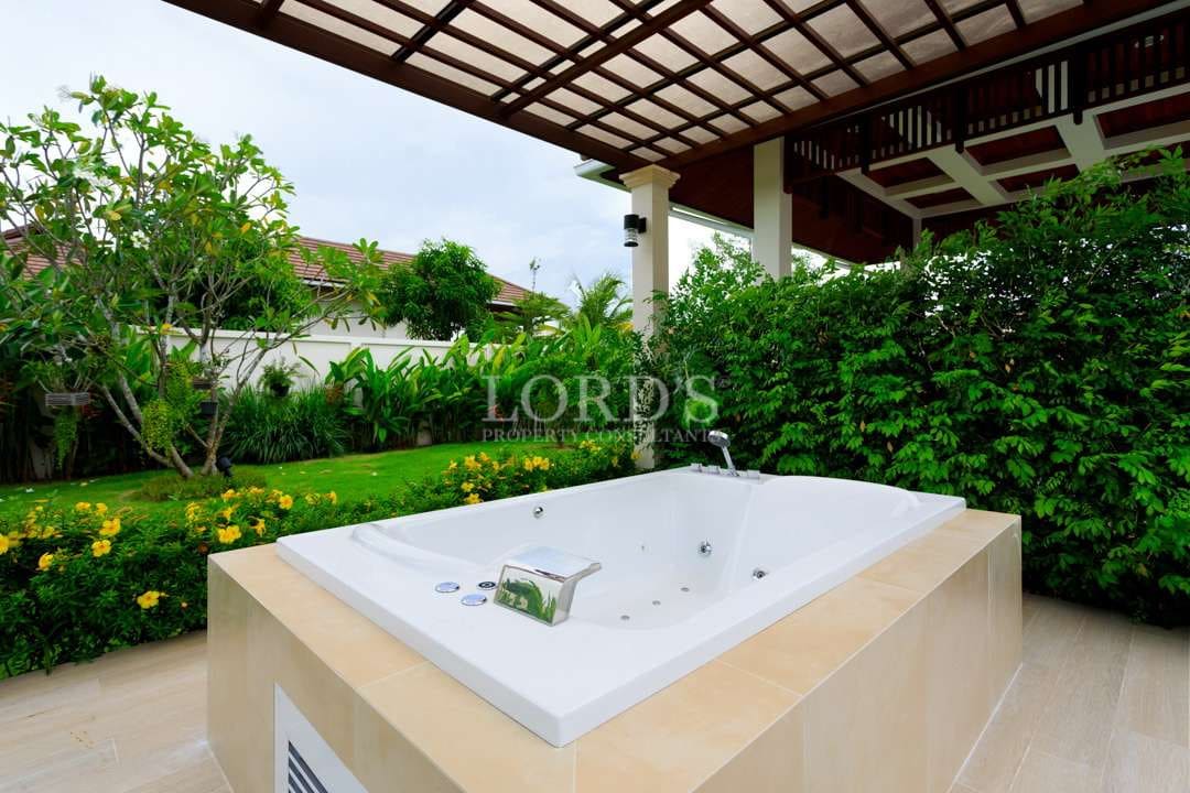 Outdoor jacuzzi in luxury villa garden with covered pavilion and lush tropical landscaping