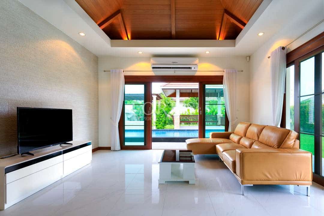 Modern living room with leather sofa, wood ceiling, and sliding doors opening to private pool