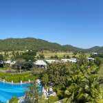 Aerial view of luxury residential area with swimming pool, palm trees, and mountain backdrop
