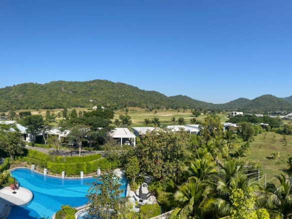 Aerial view of luxury residential area with swimming pool, palm trees, and mountain backdrop