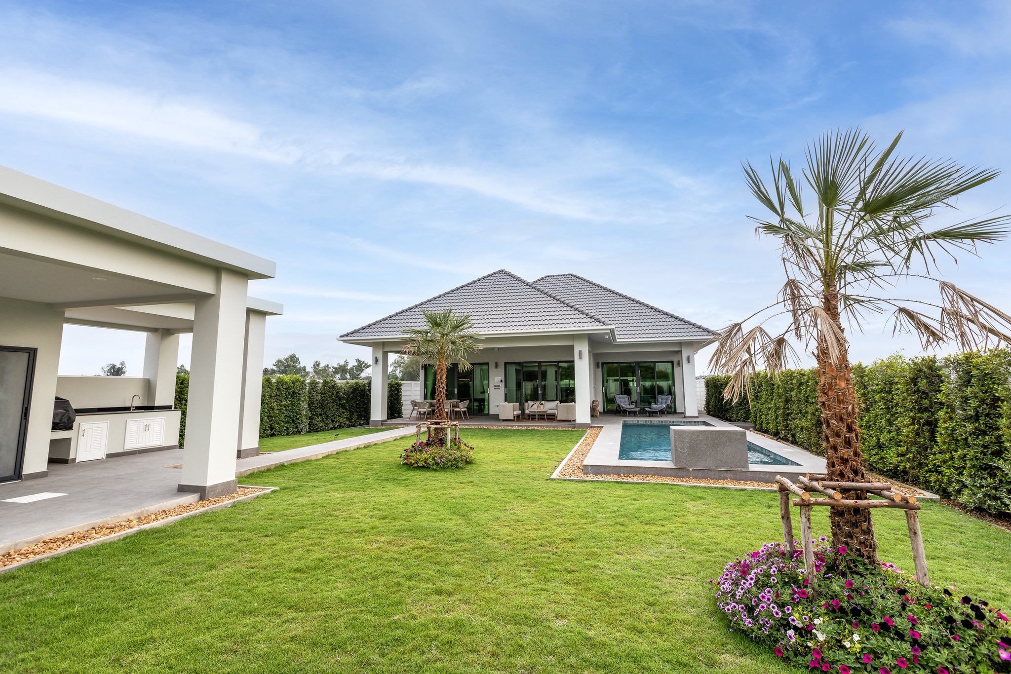 Modern villa with private swimming pool, green lawn, and outdoor kitchen