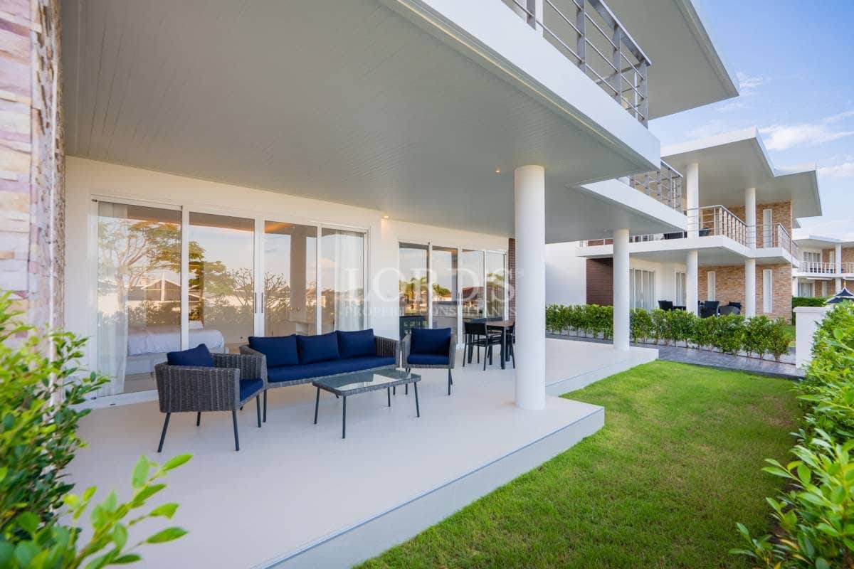 Covered ground-floor terrace with outdoor seating, garden access, and modern villa architecture.