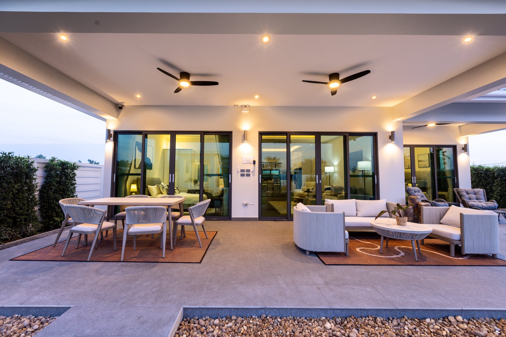 Modern outdoor patio with dining and lounge seating under covered terrace lighting.