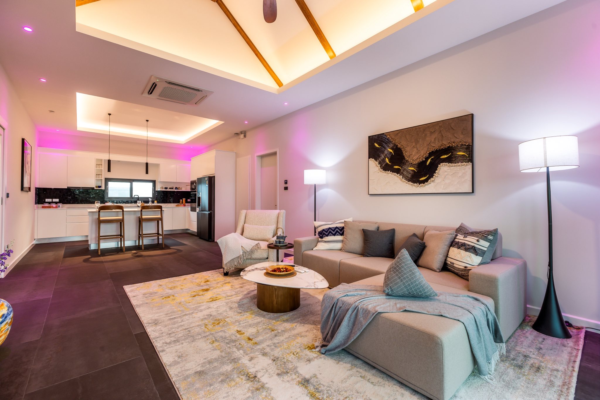 Modern open-plan living room with ambient LED lighting, vaulted ceiling, and integrated kitchen.