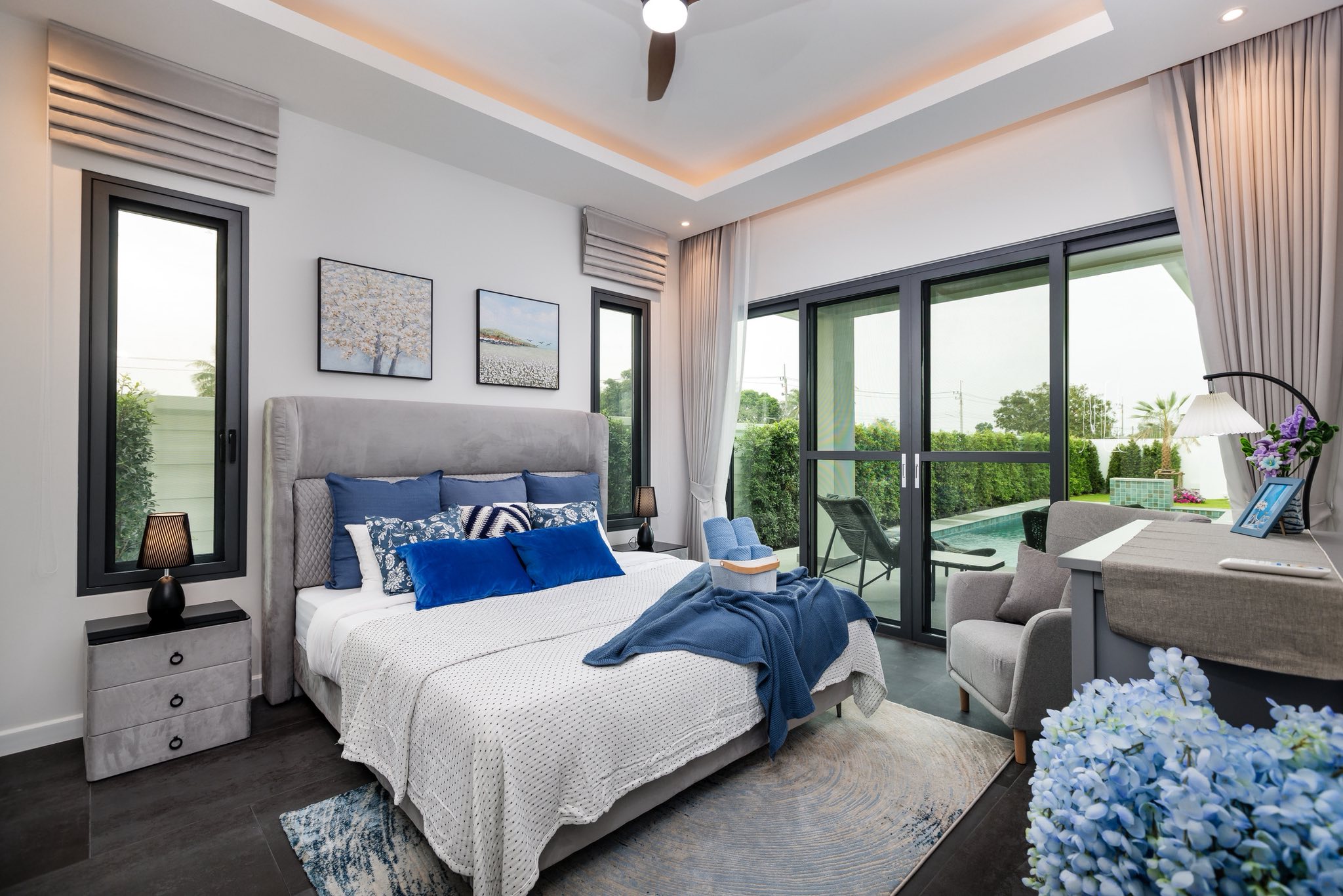 Modern bedroom with pool view, large glass sliding doors, stylish bed, and contemporary décor.