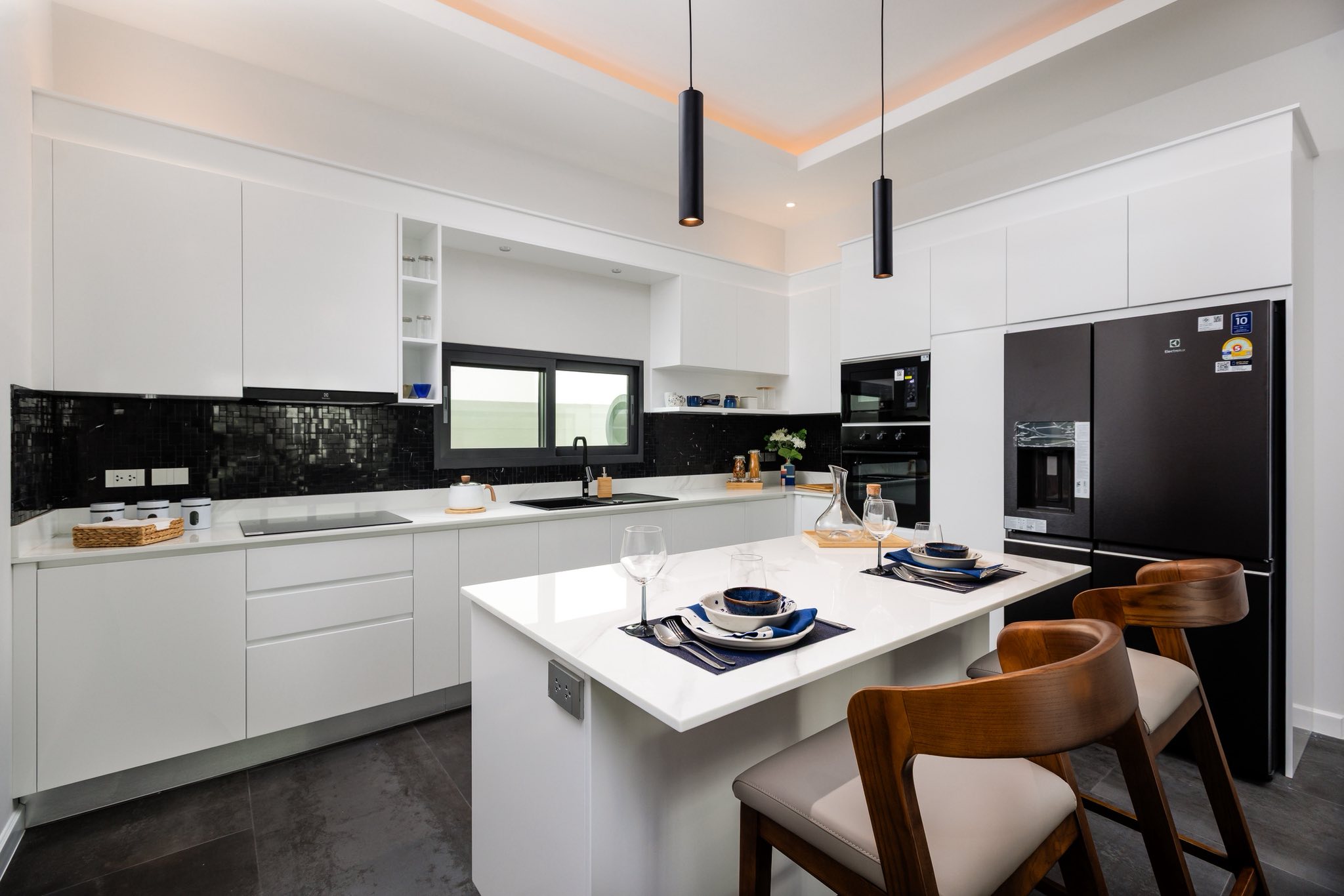 Modern white kitchen with island, bar stools, built-in appliances, and minimalist design.