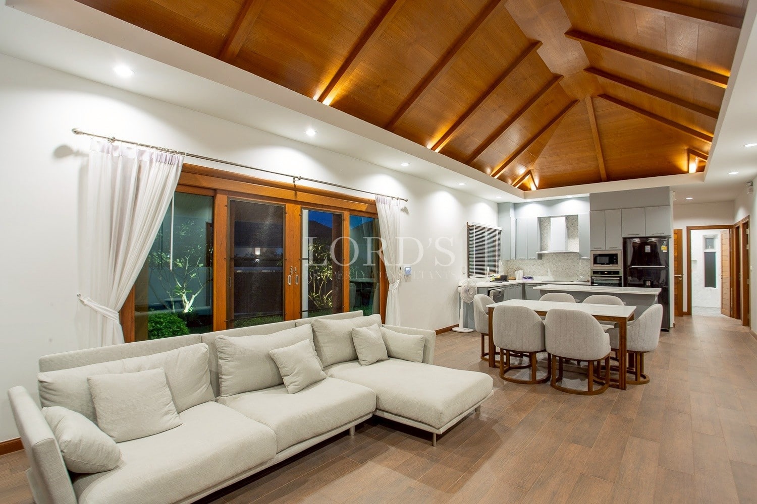 Open-plan living room with sectional sofa, wooden ceiling, and dining area