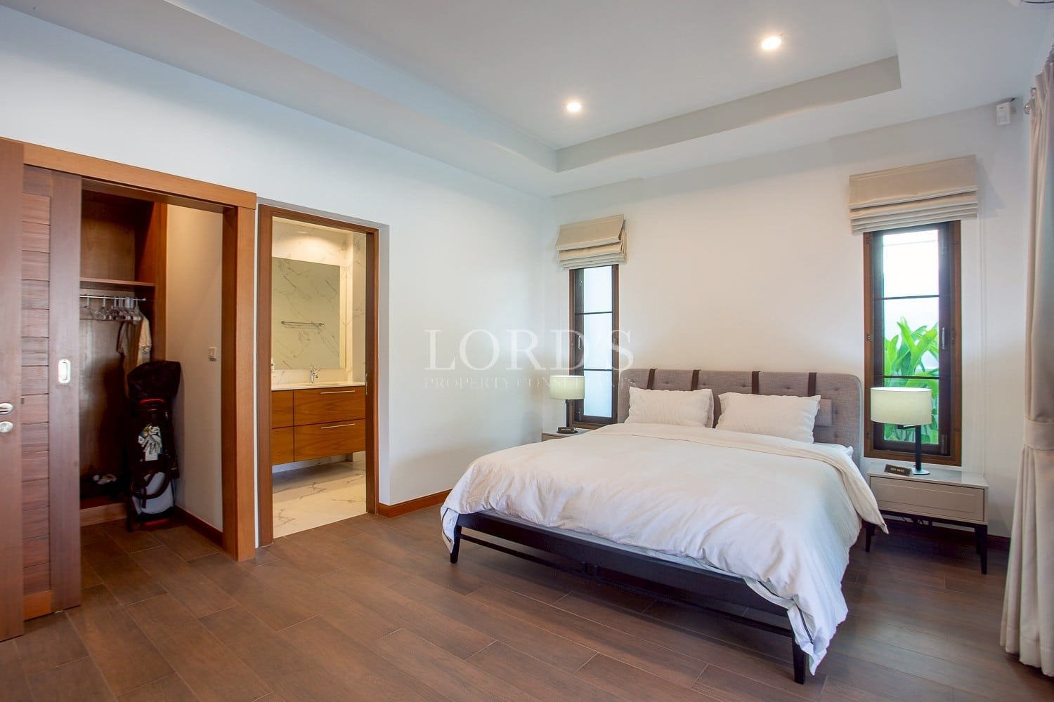 Modern bedroom with double bed, wooden flooring, and ensuite bathroom
