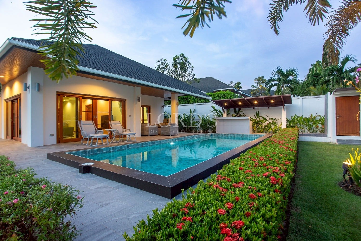 Modern villa with private swimming pool, garden landscaping, and outdoor seating area