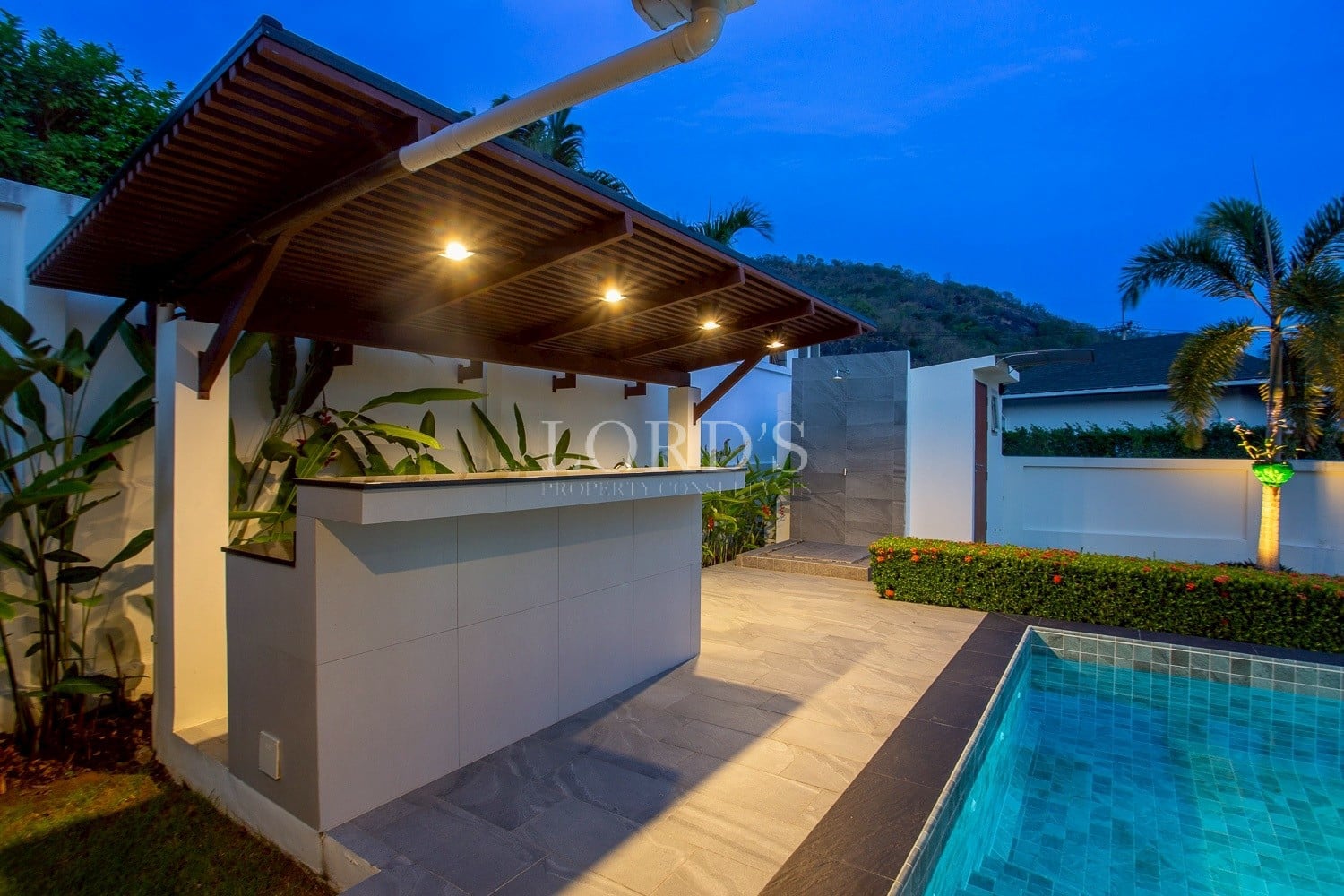 Poolside outdoor bar with covered roof and ambient lighting at night