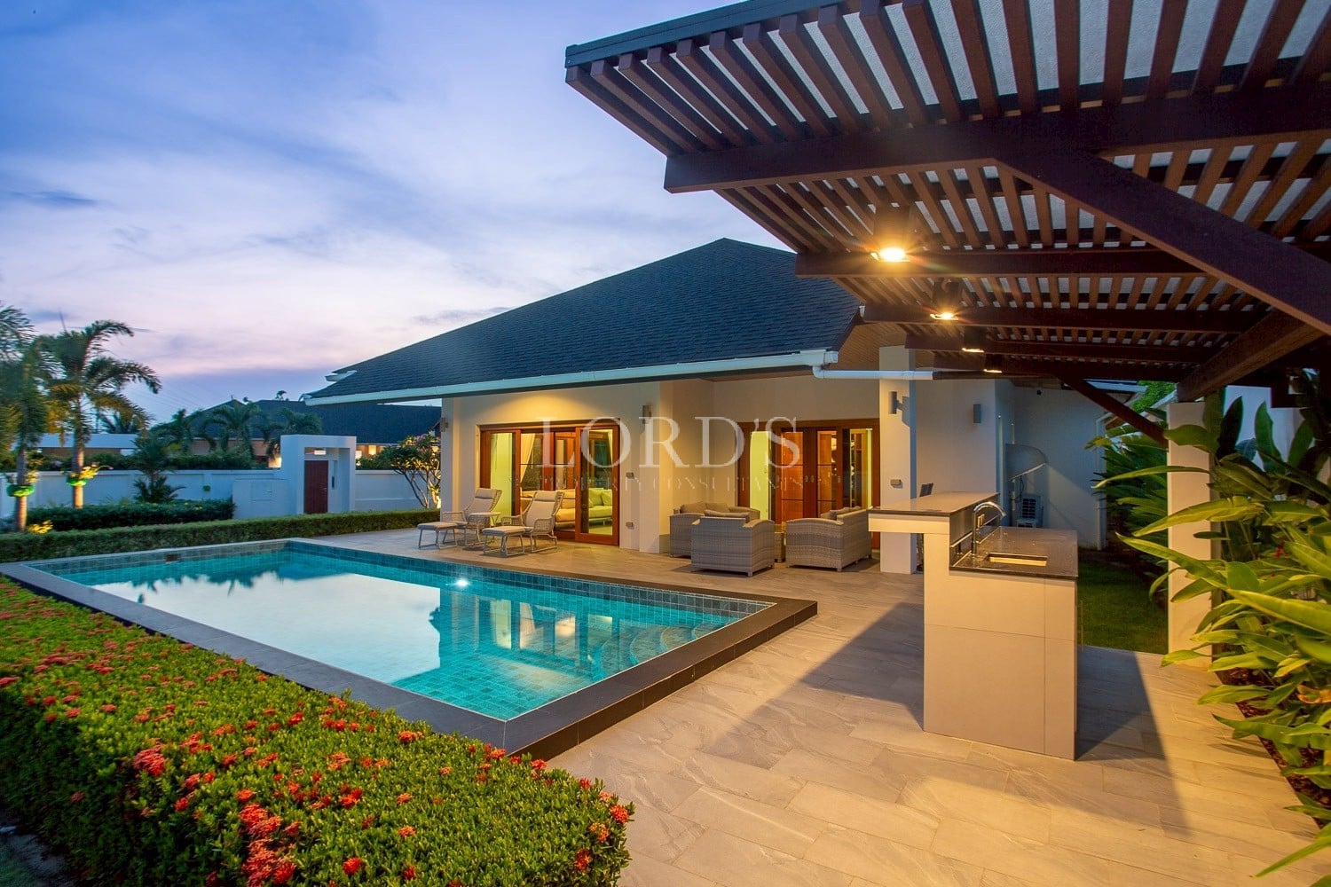 Modern luxury villa with private swimming pool, outdoor sElegant modern villa with a private pool and stylish outdoor living areaeating, and covered patio at dusk