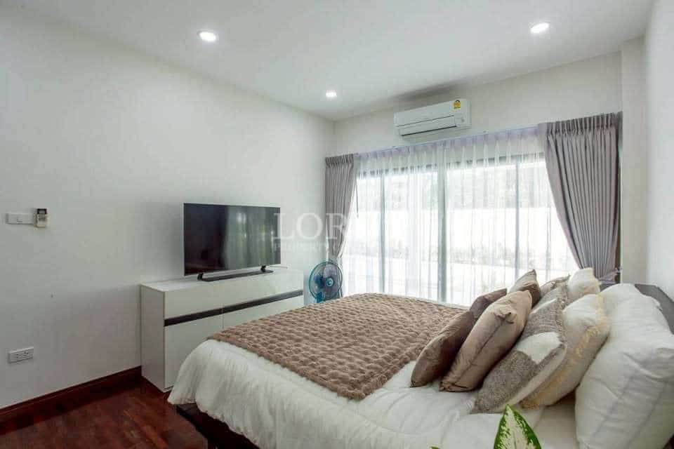 Modern bedroom with double bed, wall-mounted TV, air conditioning, sliding glass doors, and soft neutral décor