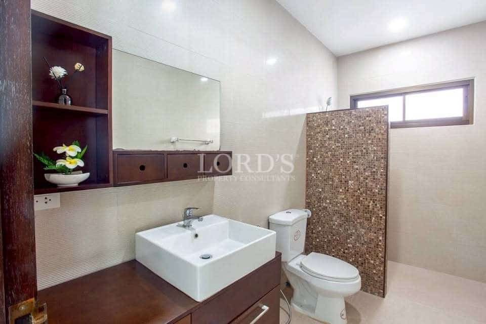 Modern bathroom with square sink vanity, wall mirror, wooden cabinetry, toilet, and tiled shower partition