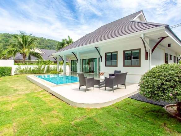 Modern single-story villa with private swimming pool, outdoor seating area, manicured lawn, and covered terrace
