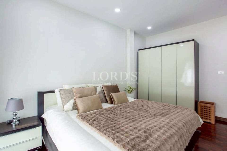 Modern bedroom with double bed, neutral bedding, built-in wardrobe, wooden flooring, and recessed ceiling lights