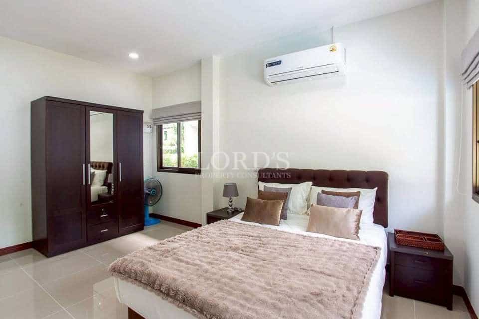 Modern bedroom with double bed, padded headboard, tiled floor, wardrobe, and wall-mounted air conditioner