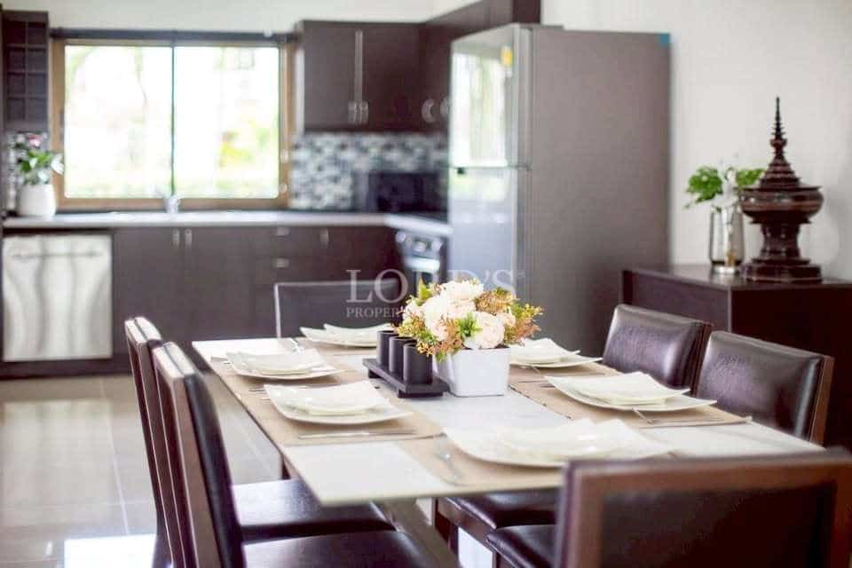 Modern dining table set for six with open kitchen in the background, dark wood cabinetry, and natural light
