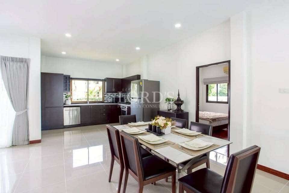 Modern open-plan dining area with glass dining table, contemporary kitchen, glossy tiled floor, and natural light
