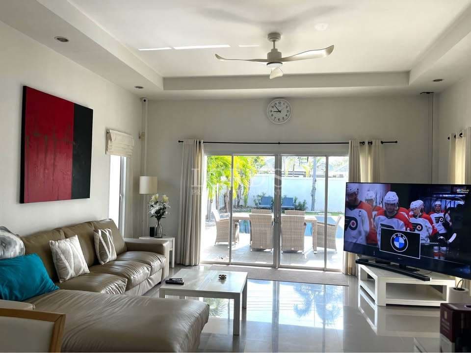 Modern living room with sectional sofa, ceiling fan, large TV, sliding glass doors, and outdoor seating view