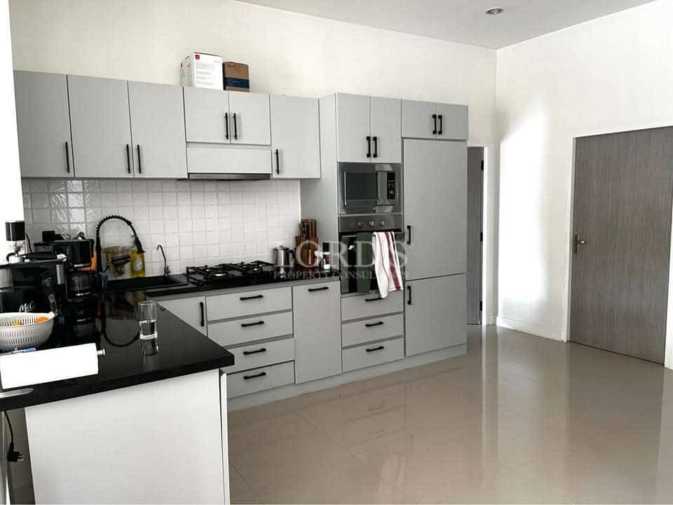 Modern kitchen with light grey cabinets, built-in oven and microwave, black countertops, and glossy tiled floor