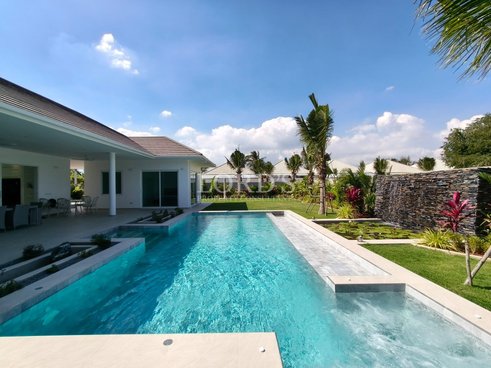 Luxurious poolside villa with greenery.